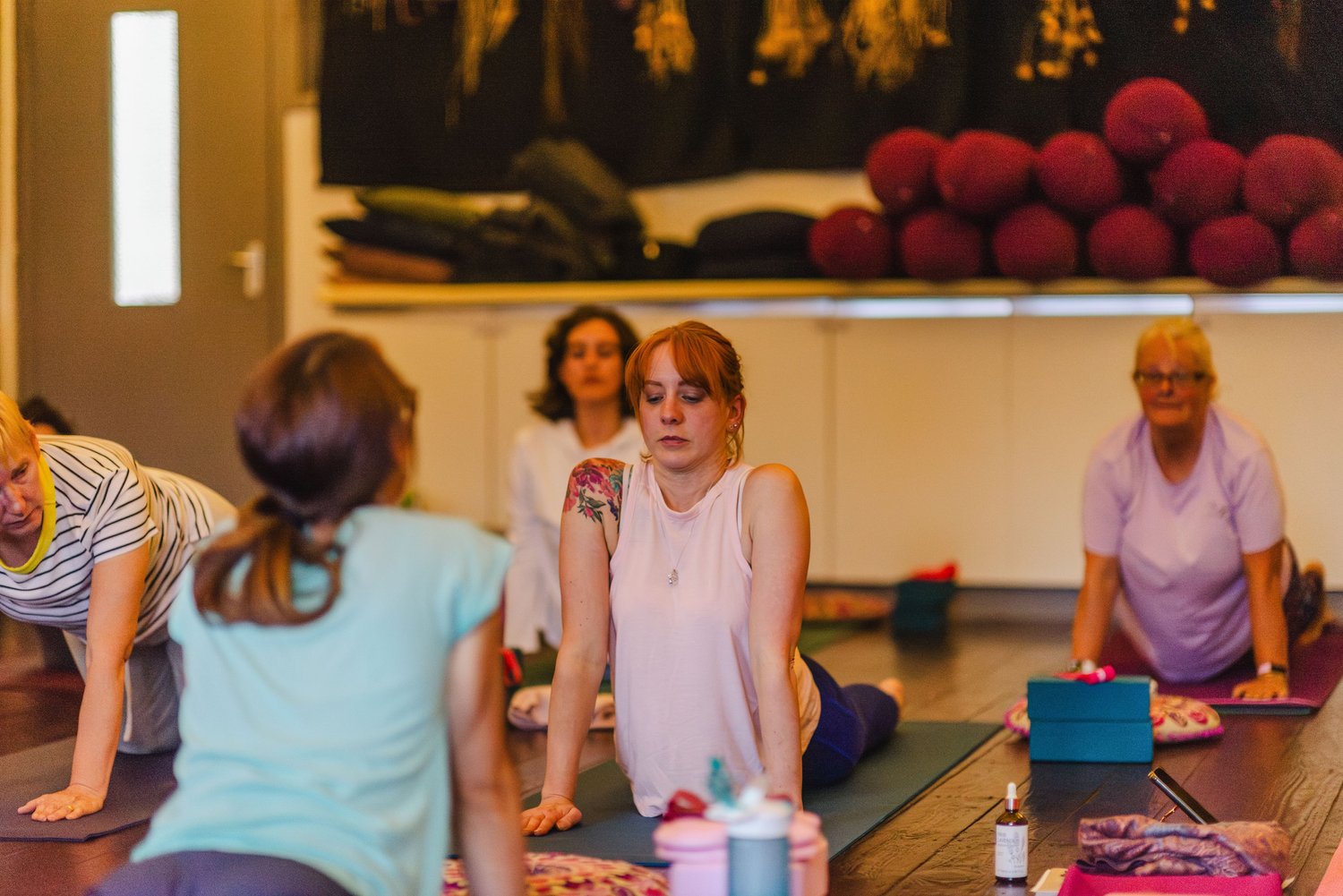 A group of women in a yoga class performing seated and floor poses